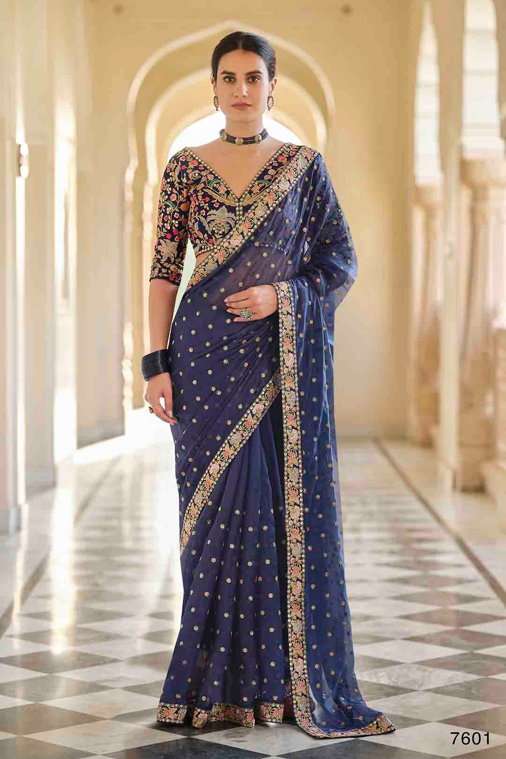 Woman wearing a blue organza saree with gold patterns. Non stitched Art silk Blouse.